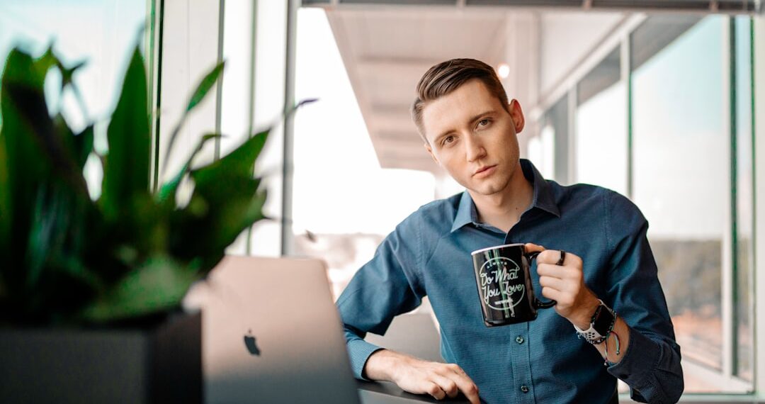 Male at work drinking coffee while working on his computer.