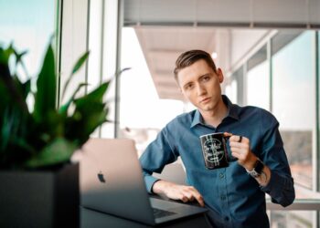 Male at work drinking coffee while working on his computer.
