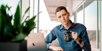 Male at work drinking coffee while working on his computer.