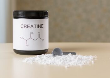 Creatine supplement jar and scoop with powder, muscle recovery and fitness