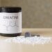 Creatine supplement jar and scoop with powder, muscle recovery and fitness