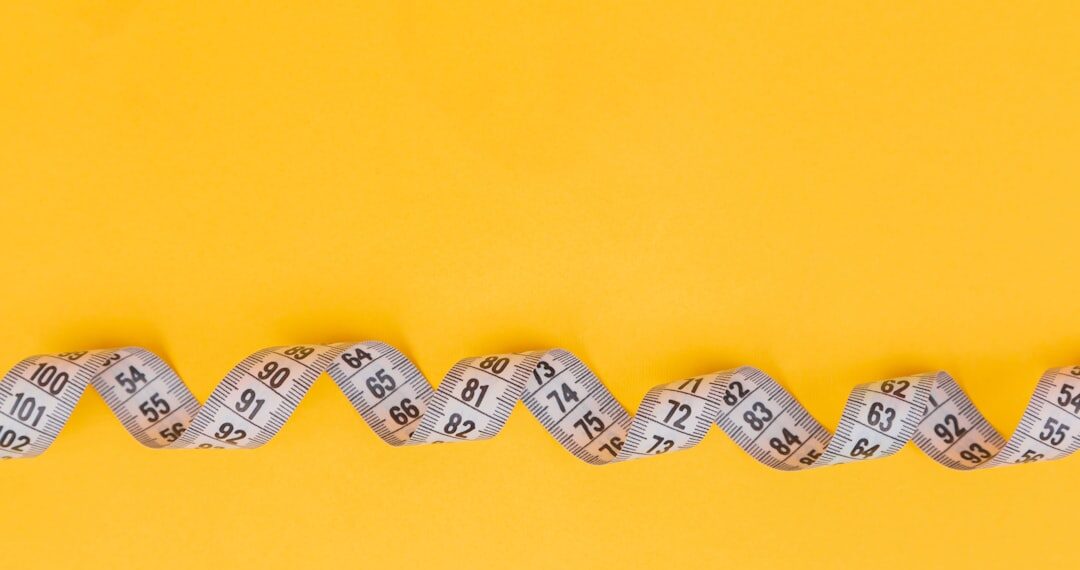 White measuring tape on a yellow background. Diet. Slimming. Obesity. Place for an inscription. Weight loss marathon. Advertising. Top view. The close plan.