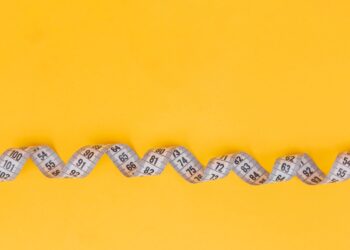 White measuring tape on a yellow background. Diet. Slimming. Obesity. Place for an inscription. Weight loss marathon. Advertising. Top view. The close plan.