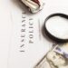 Certificate of motor insurance and policy with car and dollar bills.